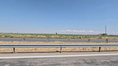 Side view of a highway next to green fields Stock Footage 283865913