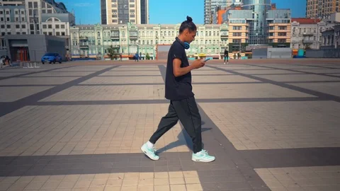 Side view hipster guy holding smartphone texting message walks in town Stock Footage 119591671