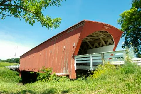 Side view of Hogback Covered Bridge with green trees and white railing Stock Photos