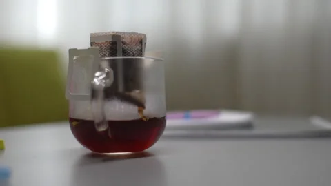 Side view of hot water pouring from kettle into drip coffee bag placed in glass Stock Footage 297630758