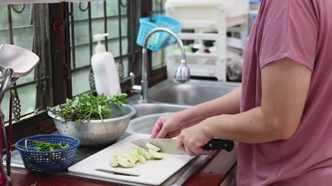 Side view of a housewife using a knife to slice fresh green Thai eggplants. Video stock 335829969