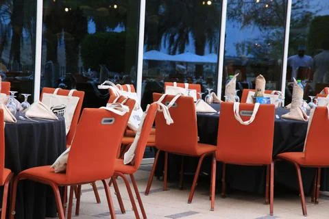 Side view of Iftar buffet Table setting, with round table and orange chairs Stock Photos