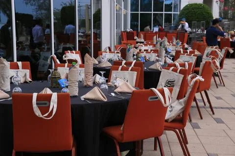 Side view of Iftar buffet Table setting, with round table and orange chairs Stock Photos