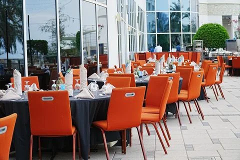 Side view of iftar setting with tables set in the row,  table and orange chairs Stock Photos