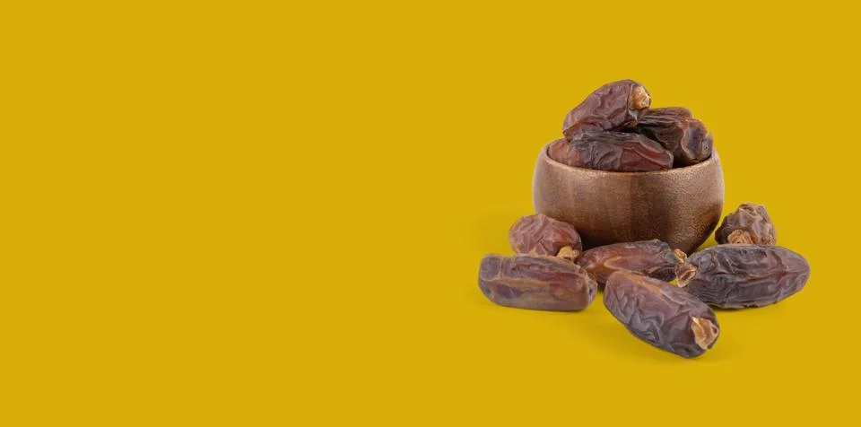 Side view image heap of date fruits in small wooden bowl. Banner concept Stock Photos