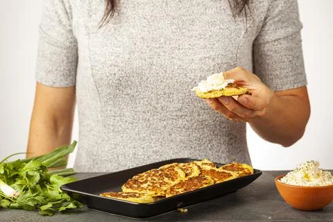 Side view image showing a caucasian woman holding a zucchini pancake known as Stock Photos