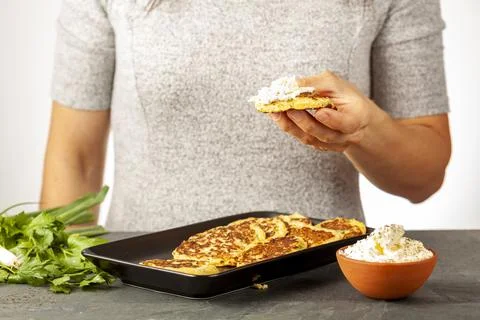 Side view image showing a caucasian woman holding a zucchini pancake known as Stock Photos