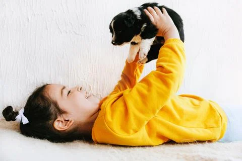 Side view image of a smiling happy child playing at home with a little dog. P Stock Photos