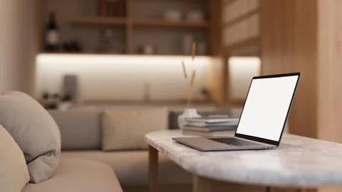 Side view image of a white-screen laptop computer on a coffee table in a mo.. 스톡 일러스트