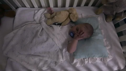 Side view of infant sleeping peacefully in white crib Stock Footage 122539344