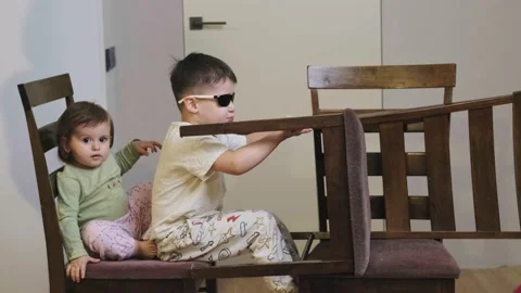 Side view of an ingenious boy playing with his sister in a makeshift car race at Video stock 171783768