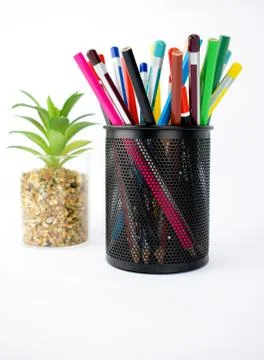 Side view of a jar full of different colored pencils and crayons beside a gre Stock Photos