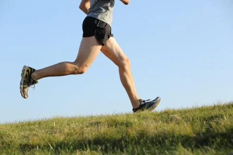 Side view of a jogger legs running on the grass Stock Photos