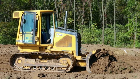 Side view of John Deere 560H LGP bulldozer pushing dirt and reversing at Stock Footage 165322036