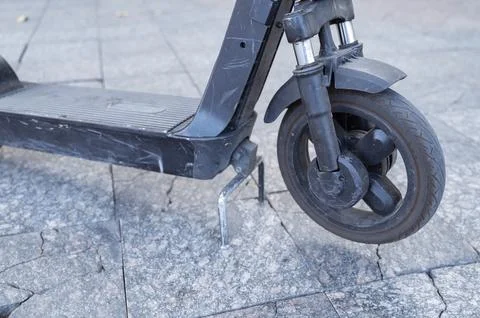 Side view of a kick scooter wheel on a paved street. Modern transportation Stock Photos