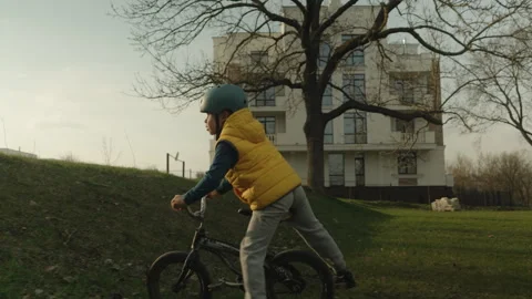 Side view of a kid boy learning to wheel, keep balance on training bicycle in Stock Footage 269140842