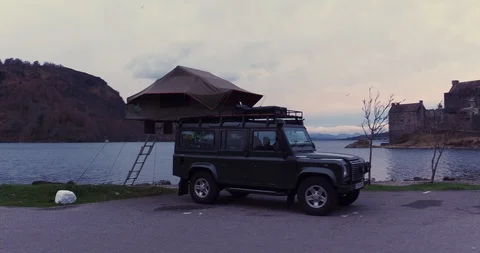 Side on view of Land Rover Defender reveals Eilean Donan Castle drone aerial 4K Stock Footage 104584451