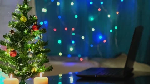 Side view a laptop and Christmas tree with ornaments and blinking lights. 動画素材 256384528