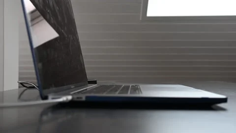 Side view of a laptop on a desk with the keyboard and a white cable Stock Footage 212344976