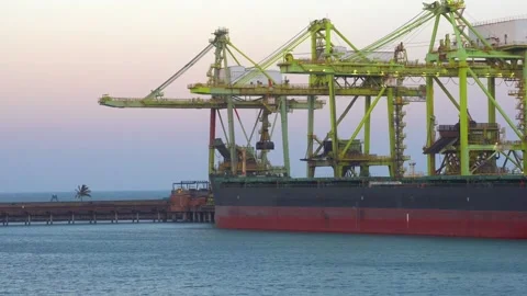 Side view of a large bulk carrier vessel unloading at a commercial sea port Stock Footage 345936708