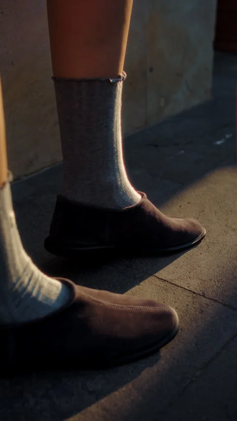Side view of legs in slippers and socks on sunlit pavement Stock Footage 317335874
