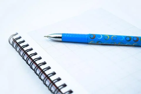 Side view of a light blue colored pen placed on top of a simple open white pa Stock Photos