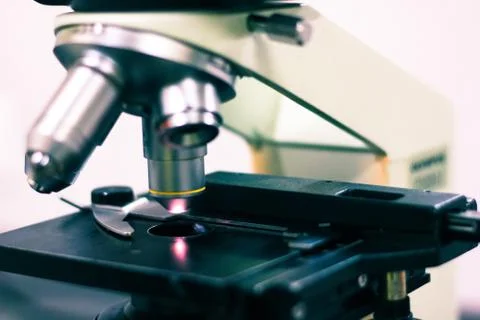 Side view of a light microscope showing the light on and optical eye piece ma Stock Photos