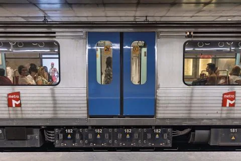 Side view of a Lisbon Metro train car stopped at a station. Passengers are vi Stock Photos