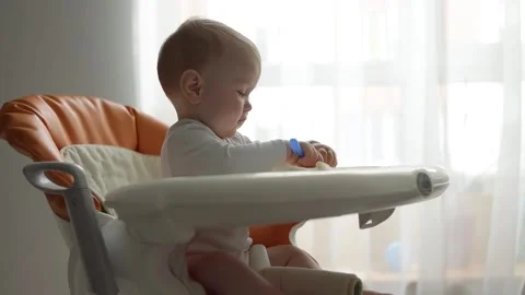 Side view. Little boy eats baby food in a feeding chair. Stock Footage 133439718