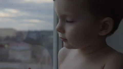 Side view of a little boy looking out of the window at the city Stock Footage 331037483