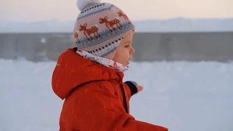 Side view of a little cute curious girl in a red suit walks Vídeos de archivo 117218210