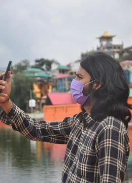Side view of a long haired young man taking selfie or having video call  Stock Photos