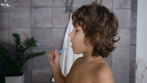 Side view of lovely dark-haired little boy which cleaning his teeth using Stock Footage 120305145