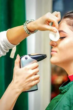 Side view of a make-up artist using aerograph making an airbrush makeup Stock Photos