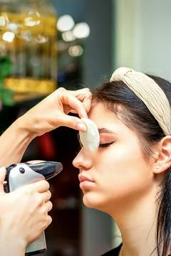 Side view of a make-up artist using aerograph making an airbrush makeup found Stock Photos