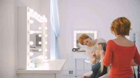 Side view of makeup artist and hairdresser preparing blonde model for the future Stock Footage 74425500