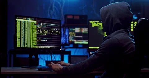 Side view on the male anonymous hacker in the hood creating virus while coding Stock Footage 124348019