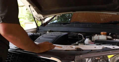 Side view of a male driver opening the front hood of a white car to inspect.. Stock Footage 329744159