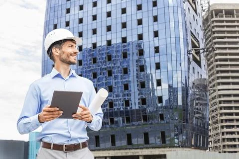 Side view of male engineer standing against background of buildings under con Stock Photos