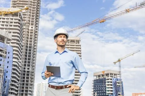 Side view of male engineer standing against background of buildings under con Stockfoto's
