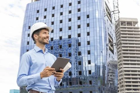 Side view of male engineer standing against background of buildings under c.. Stockfoto's