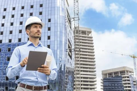 Side view of male engineer standing against background of buildings under c.. Stockfoto's