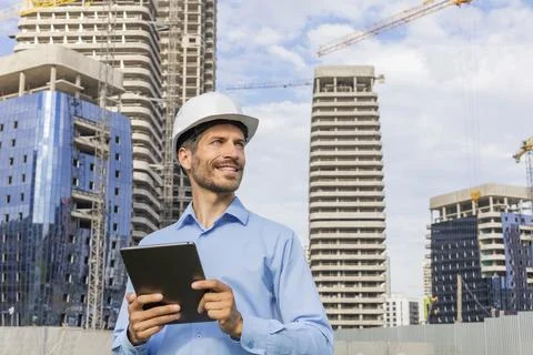 Side view of male engineer standing against background of buildings under c.. Stockfoto's