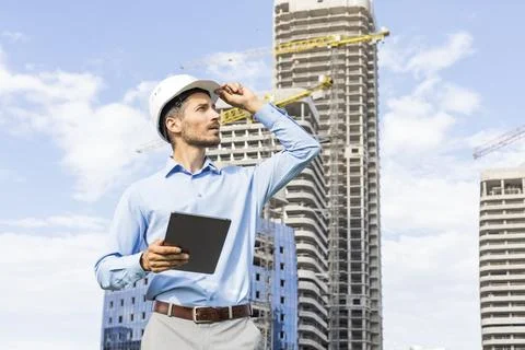 Side view of male engineer standing against background of buildings under con Stockfoto's