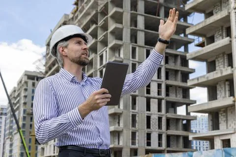 Side view of male engineer standing against background of buildings under c.. Foto stock