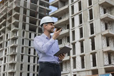 Side view of male engineer standing against background of buildings under c.. Foto stock