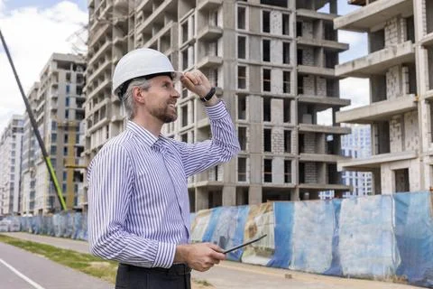 Side view of male engineer standing against background of buildings under c.. Foto stock