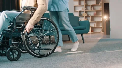 Side view male hands rolling wheelchair wheels riding in sunshine at home Video stock 244653814