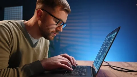 Side view. Male programmer is working indoors by a laptop. Stock Footage 297673345