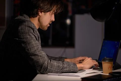 Side View On Male Programmer Writing Code on Computer at Night. Table Light Fotos Stock